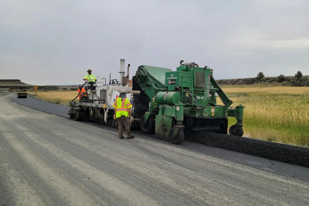 Paving train placing asphalt on a rural road